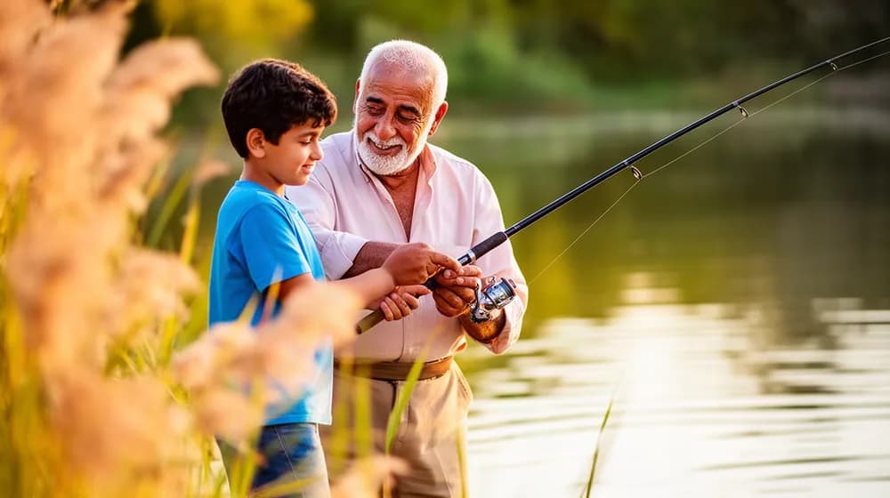 Un grand-père apprend à son petit-fils à tenir une canne à pêche au bord d’un étang