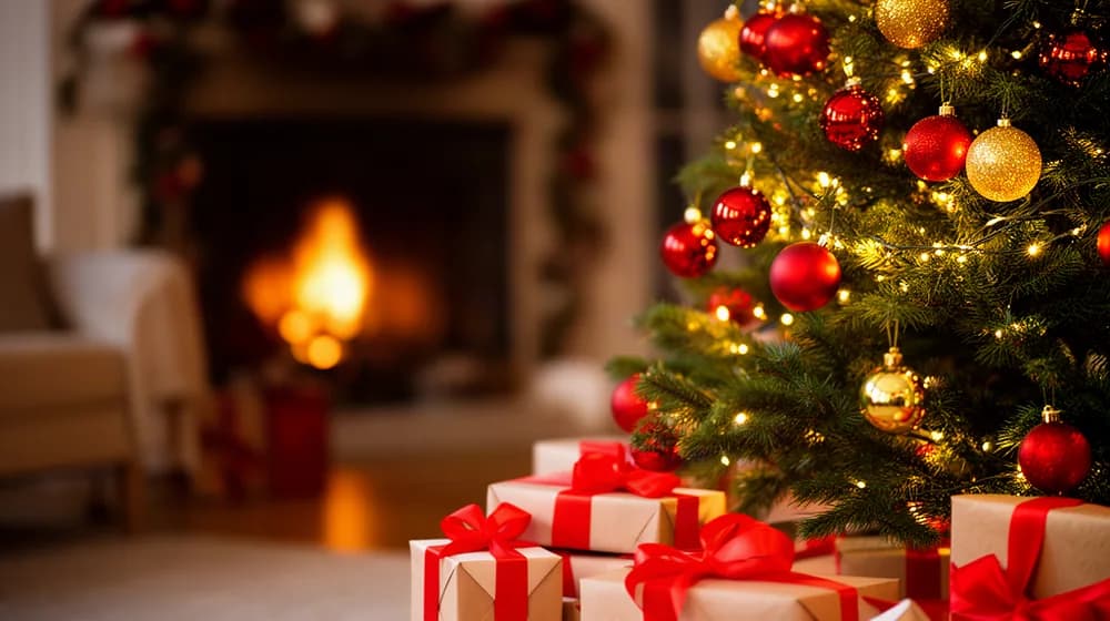 Un sapin décoré et illuminé, des paquets cadeaux à son pied dans un salon le soir